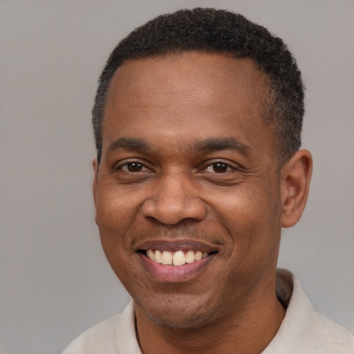 Joyful black adult male with short  black hair and brown eyes