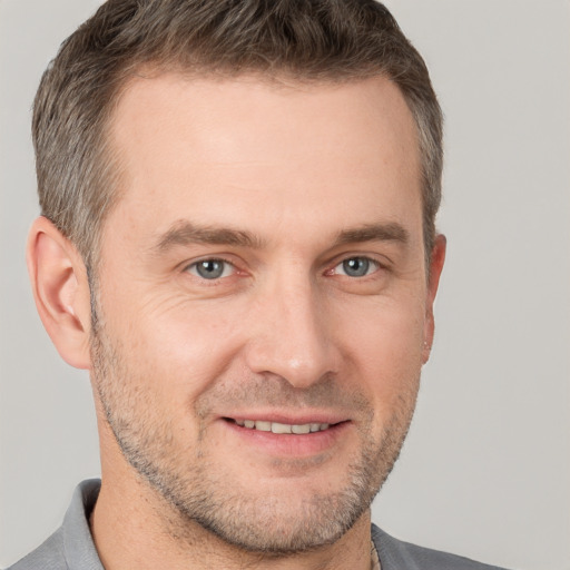 Joyful white adult male with short  brown hair and grey eyes