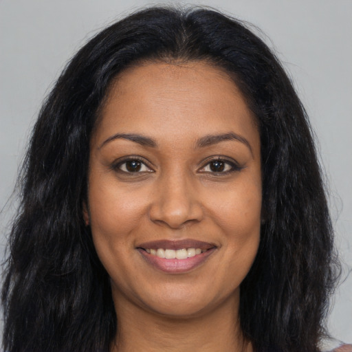 Joyful black young-adult female with long  brown hair and brown eyes