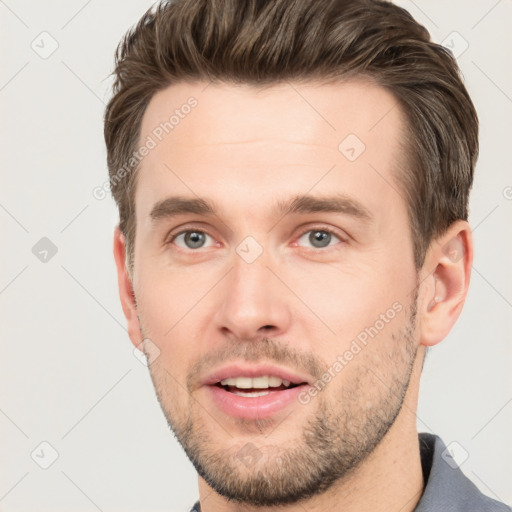 Joyful white young-adult male with short  brown hair and grey eyes