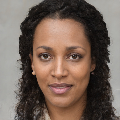 Joyful black young-adult female with long  brown hair and brown eyes