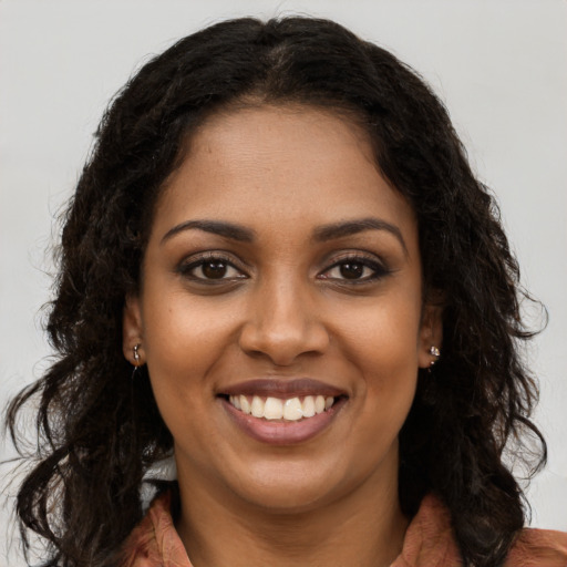 Joyful black young-adult female with long  brown hair and brown eyes