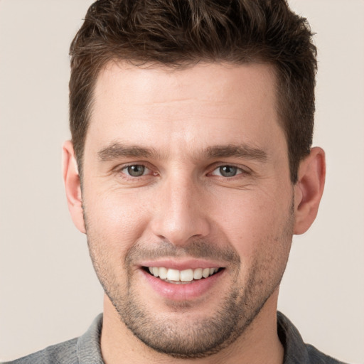 Joyful white young-adult male with short  brown hair and grey eyes