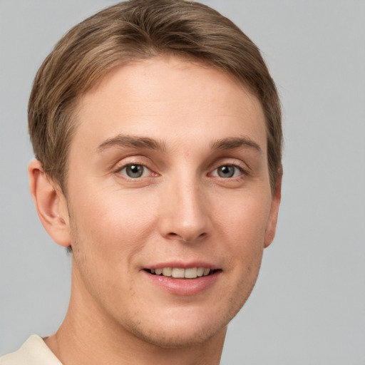 Joyful white young-adult male with short  brown hair and grey eyes