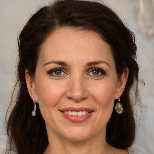 Joyful white adult female with long  brown hair and green eyes