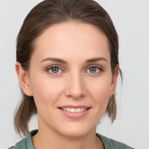 Joyful white young-adult female with medium  brown hair and grey eyes