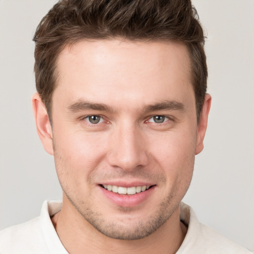 Joyful white young-adult male with short  brown hair and grey eyes