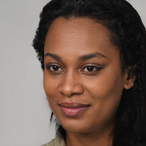 Joyful black young-adult female with long  black hair and brown eyes