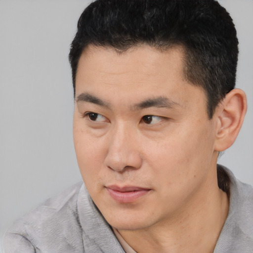 Joyful asian young-adult male with short  black hair and brown eyes