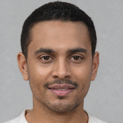 Joyful latino young-adult male with short  black hair and brown eyes