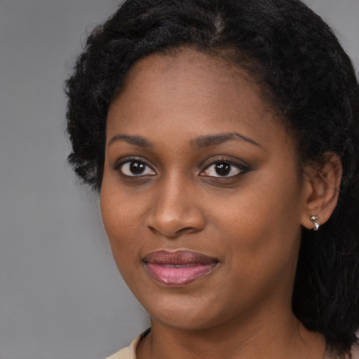 Joyful black young-adult female with long  brown hair and brown eyes