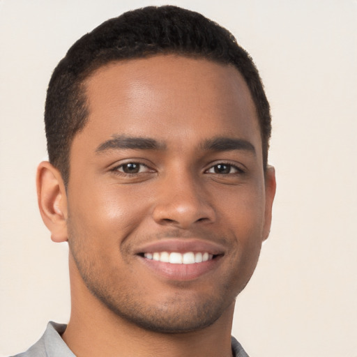 Joyful black young-adult male with short  brown hair and brown eyes