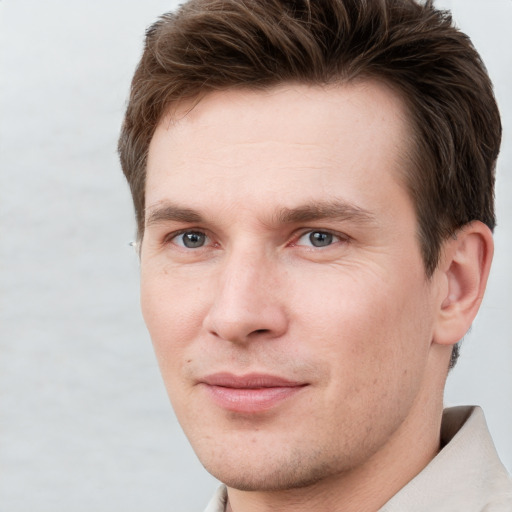 Joyful white young-adult male with short  brown hair and grey eyes