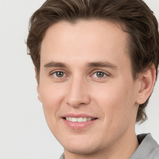 Joyful white young-adult male with short  brown hair and grey eyes