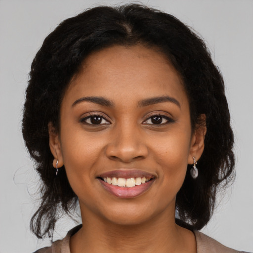 Joyful black young-adult female with long  black hair and brown eyes