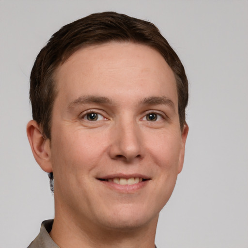 Joyful white young-adult male with short  brown hair and grey eyes