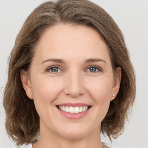 Joyful white young-adult female with medium  brown hair and grey eyes