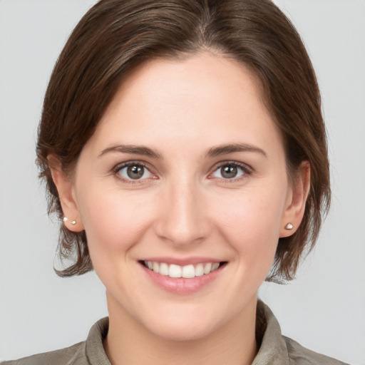 Joyful white young-adult female with medium  brown hair and grey eyes