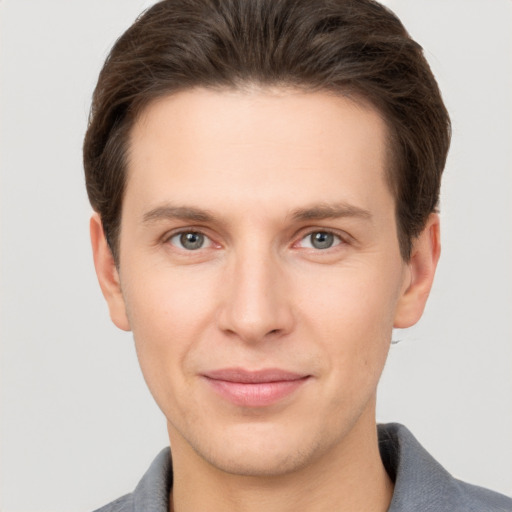 Joyful white young-adult male with short  brown hair and grey eyes