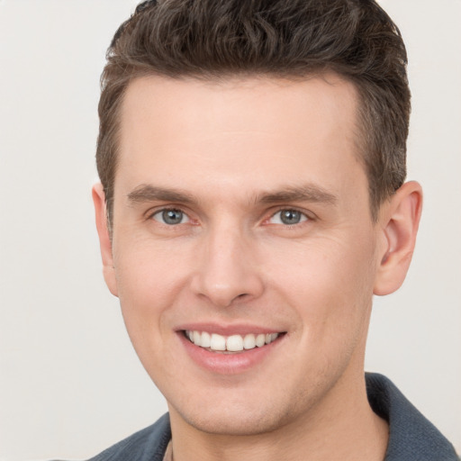 Joyful white young-adult male with short  brown hair and grey eyes