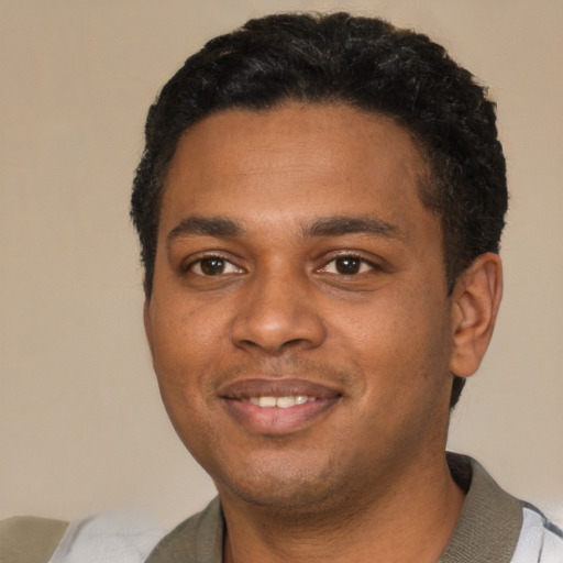 Joyful black young-adult male with short  black hair and brown eyes