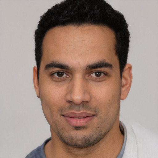 Joyful latino young-adult male with short  black hair and brown eyes