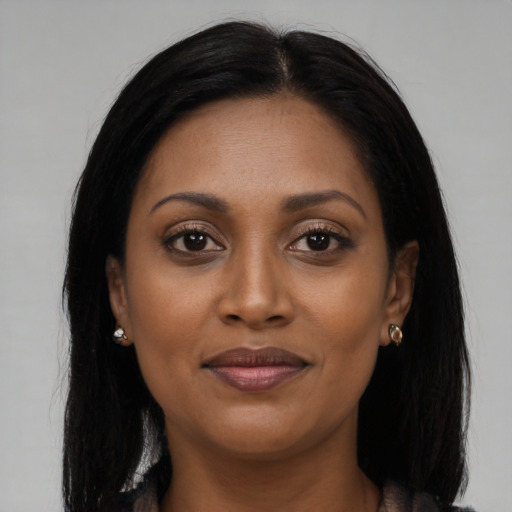 Joyful black young-adult female with long  brown hair and brown eyes