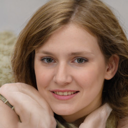 Joyful white young-adult female with long  brown hair and blue eyes