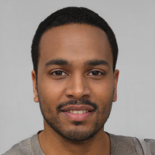Joyful black young-adult male with short  black hair and brown eyes