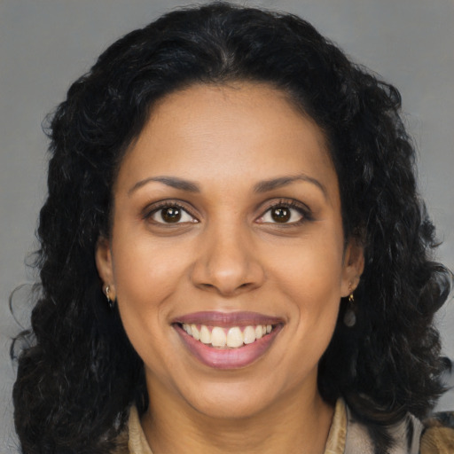 Joyful black young-adult female with long  brown hair and brown eyes