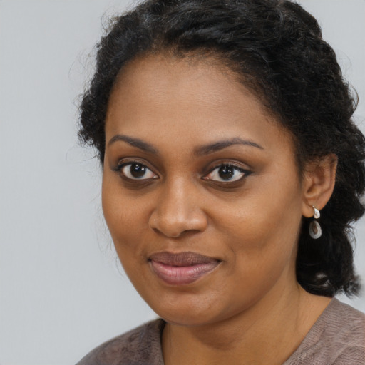 Joyful black young-adult female with long  brown hair and brown eyes