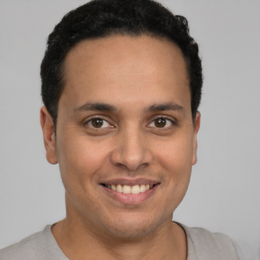 Joyful latino young-adult male with short  brown hair and brown eyes
