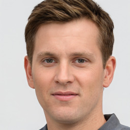 Joyful white young-adult male with short  brown hair and grey eyes