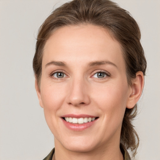 Joyful white young-adult female with medium  brown hair and grey eyes