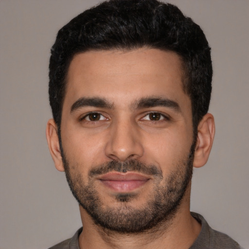 Joyful latino young-adult male with short  black hair and brown eyes