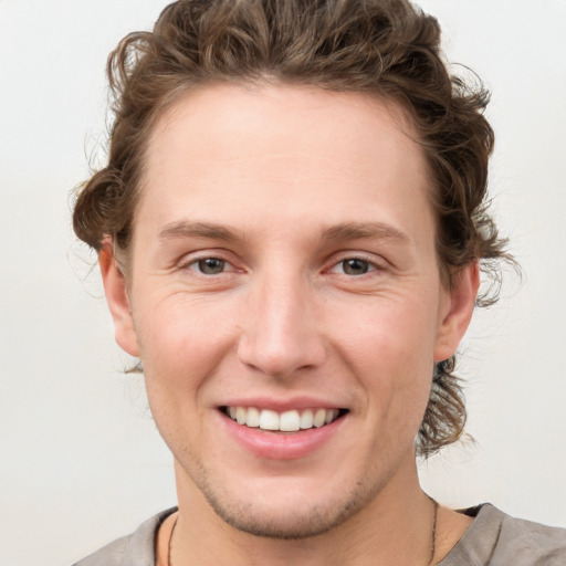 Joyful white young-adult male with medium  brown hair and grey eyes