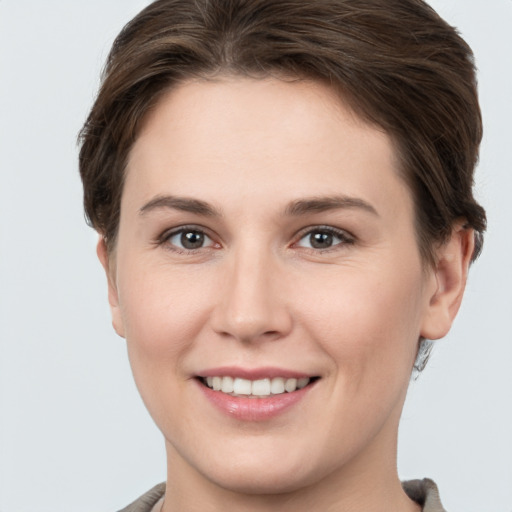 Joyful white young-adult female with short  brown hair and grey eyes