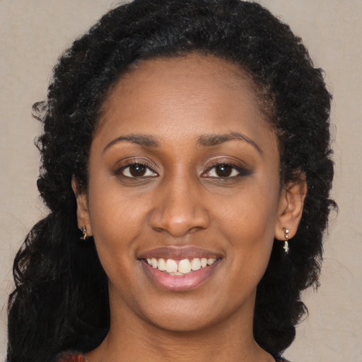 Joyful black young-adult female with long  brown hair and brown eyes