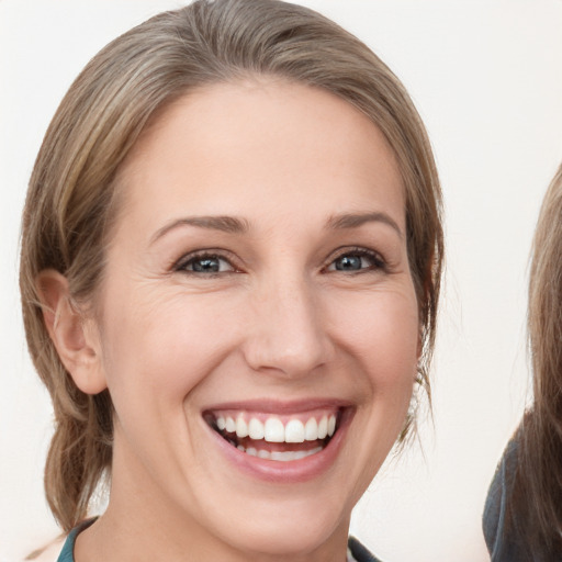 Joyful white young-adult female with medium  brown hair and grey eyes