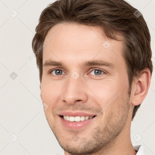 Joyful white young-adult male with short  brown hair and grey eyes