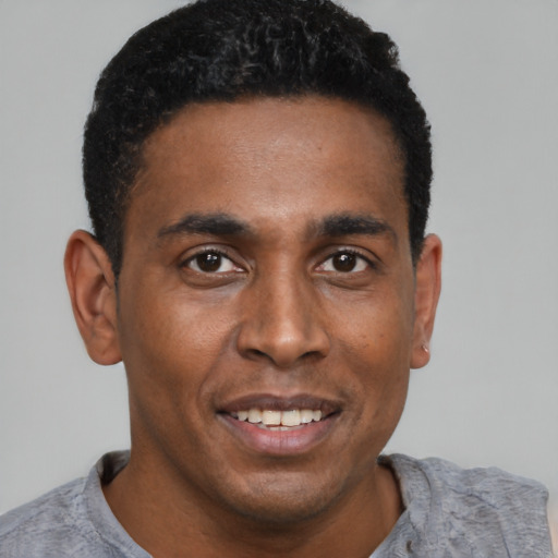 Joyful black young-adult male with short  black hair and brown eyes