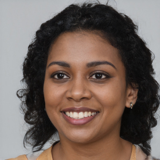 Joyful black young-adult female with long  brown hair and brown eyes