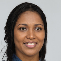 Joyful black young-adult female with long  brown hair and brown eyes