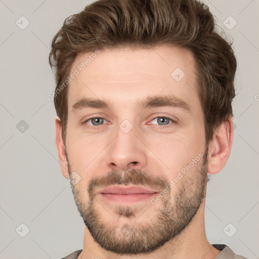 Joyful white young-adult male with short  brown hair and grey eyes