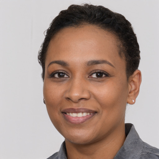 Joyful black young-adult female with short  black hair and brown eyes