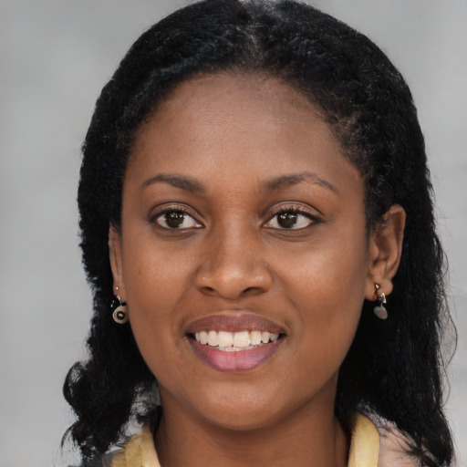 Joyful black young-adult female with long  black hair and brown eyes