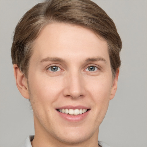 Joyful white young-adult male with short  brown hair and grey eyes