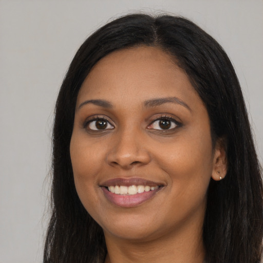 Joyful black young-adult female with long  brown hair and brown eyes