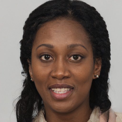 Joyful black young-adult female with long  brown hair and brown eyes