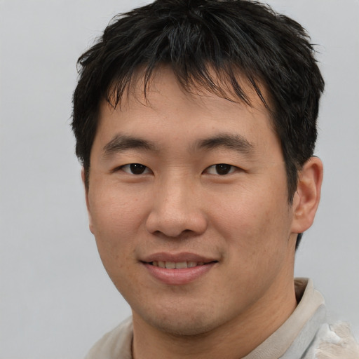 Joyful asian young-adult male with short  brown hair and brown eyes